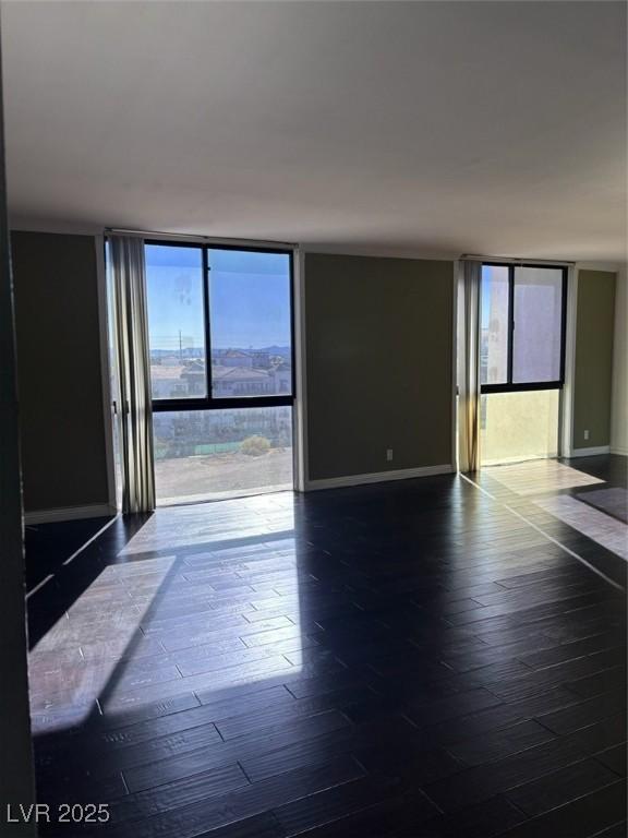 3930 University Center Dr Unit 702, Las Vegas, NV 89119 - spare room featuring baseboards, hardwood / wood-style floors, and a wall of windows