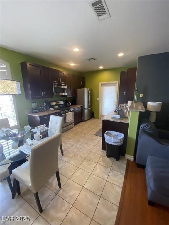 1511 Cardinal Peak Ln Unit 201, Las Vegas, NV 89144 - kitchen with appliances with stainless steel finishes, a peninsula, dark brown cabinets, light tile patterned floors, and recessed lighting