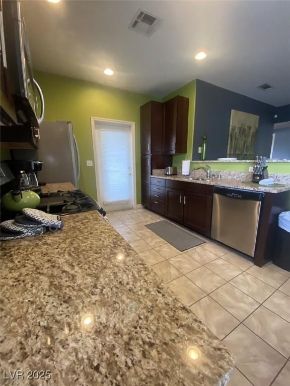 1511 Cardinal Peak Ln Unit 201, Las Vegas, NV 89144 - kitchen featuring stainless steel appliances, light tile patterned floors, a sink, dark brown cabinetry, and light stone countertops