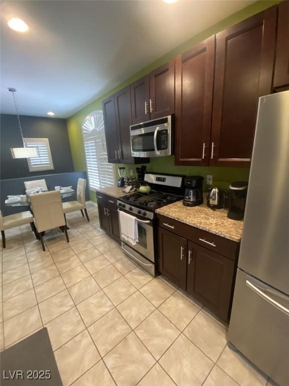 1511 Cardinal Peak Ln Unit 201, Las Vegas, NV 89144 - kitchen with appliances with stainless steel finishes, light tile patterned floors, dark brown cabinetry, hanging light fixtures, and light stone counters