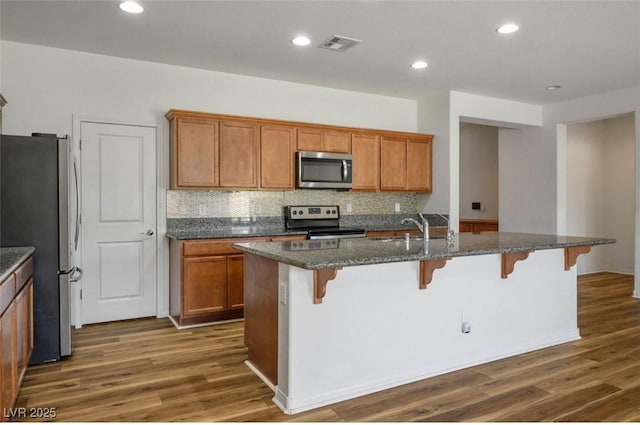 5235 E Ln Campana Dr, Pahrump, NV 89061 - kitchen featuring stainless steel appliances, wood finished floors, decorative backsplash, a breakfast bar, and recessed lighting