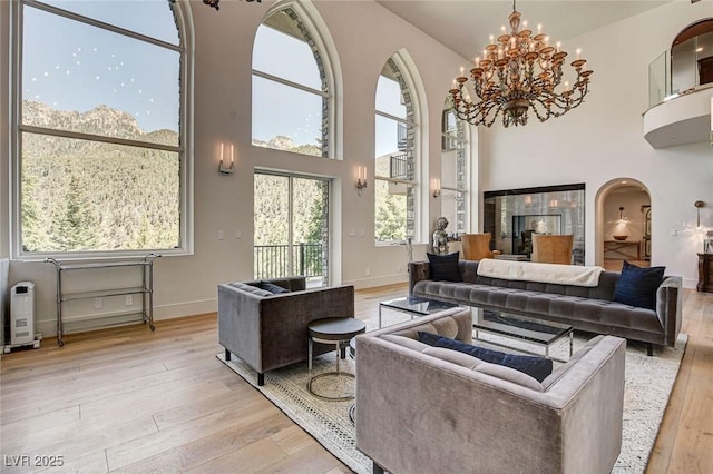 4162 Matterhorn Way, Las Vegas, NV 89124 - living area with wood-type flooring, arched walkways, a chandelier, a high ceiling, and baseboards