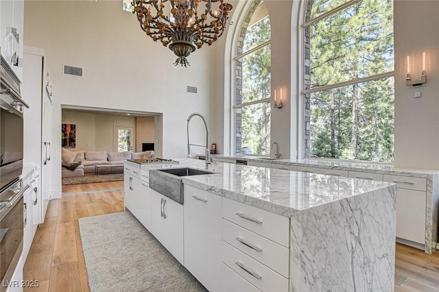 4162 Matterhorn Way, Las Vegas, NV 89124 - kitchen featuring a sink, white cabinets, light wood-style floors, and a high ceiling