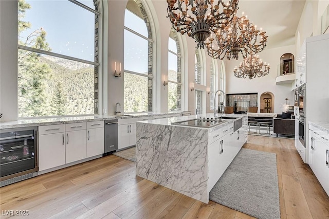 4162 Matterhorn Way, Las Vegas, NV 89124 - kitchen featuring a sink, white cabinets, light wood-style floors, plenty of natural light, and a towering ceiling