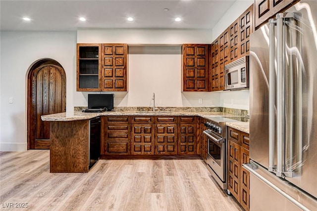 4162 Matterhorn Way, Las Vegas, NV 89124 - kitchen with high end appliances, a sink, a peninsula, light wood-style floors, and light stone countertops