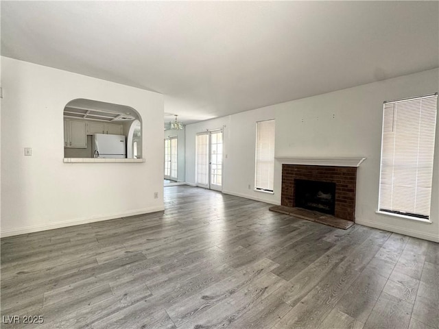 6137 W Oakey Blvd Unit A, Las Vegas, NV 89146 - unfurnished living room with wood finished floors, baseboards, a brick fireplace, a chandelier, and arched walkways