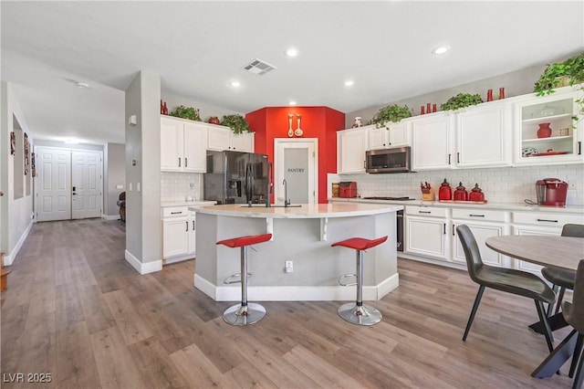 7821 Red Leaf Dr, Las Vegas, NV 89131 - kitchen with black refrigerator with ice dispenser, stainless steel microwave, tasteful backsplash, white cabinetry, and recessed lighting