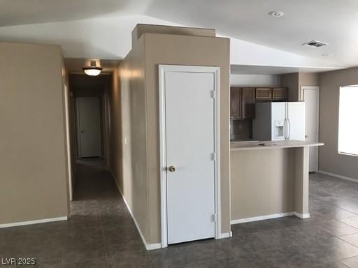 4704 Wild Oak Way N, Las Vegas, NV 89031 - kitchen with white fridge with ice dispenser, vaulted ceiling, baseboards, dark tile patterned flooring, and light countertops