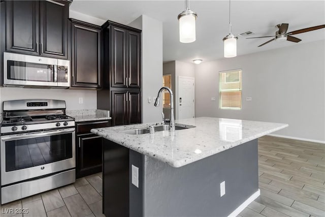 7345 Chesapeake Cove St, Las Vegas, NV 89166 - kitchen featuring stainless steel appliances, a sink, wood tiled floors, and an island with sink