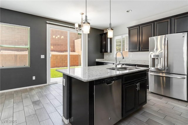 7345 Chesapeake Cove St, Las Vegas, NV 89166 - kitchen featuring appliances with stainless steel finishes, a sink, an island with sink, light stone countertops, and pendant lighting