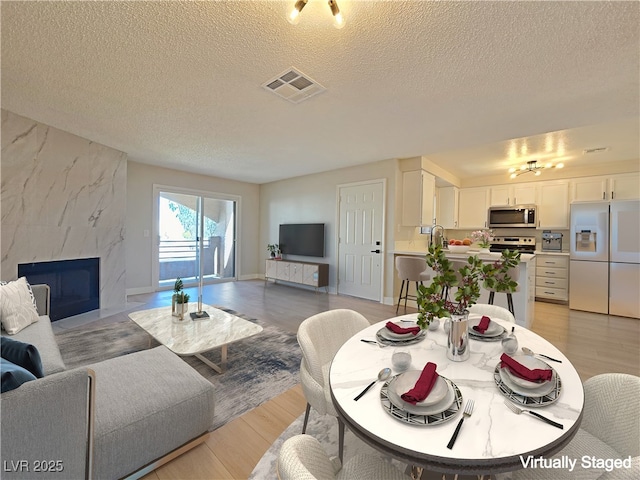 6853 Tamarus St Unit 202, Las Vegas, NV 89119 - living area with a textured ceiling, light wood-type flooring, and a high end fireplace