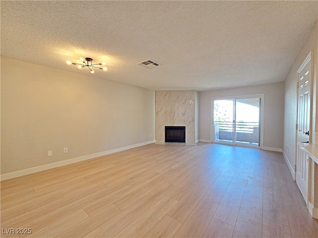 6853 Tamarus St Unit 202, Las Vegas, NV 89119 - unfurnished living room with a textured ceiling, light wood-type flooring, a premium fireplace, and baseboards