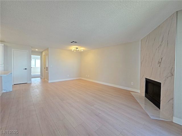 6853 Tamarus St Unit 202, Las Vegas, NV 89119 - unfurnished living room featuring a textured ceiling, a fireplace, light wood-type flooring, and baseboards
