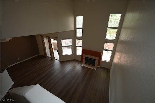 5125 W Reno Ave Unit 1059, Las Vegas, NV 89118 - unfurnished living room featuring dark wood finished floors, plenty of natural light, baseboards, and a tiled fireplace