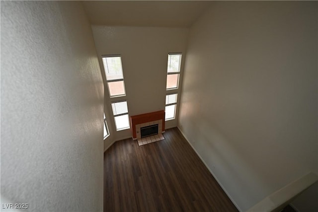 5125 W Reno Ave Unit 1059, Las Vegas, NV 89118 - unfurnished living room featuring dark wood-style floors, baseboards, a textured wall, and a tile fireplace
