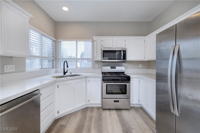 7836 Pinnochio Ave, Las Vegas, NV 89131 - kitchen with stainless steel appliances, a sink, light wood finished floors, white cabinetry, and light countertops