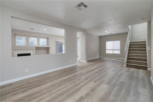 7836 Pinnochio Ave, Las Vegas, NV 89131 - unfurnished living room featuring a tile fireplace, wood finished floors, arched walkways, baseboards, and recessed lighting