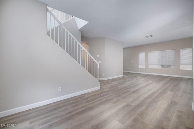 7836 Pinnochio Ave, Las Vegas, NV 89131 - unfurnished living room featuring baseboards, wood finished floors, and stairway