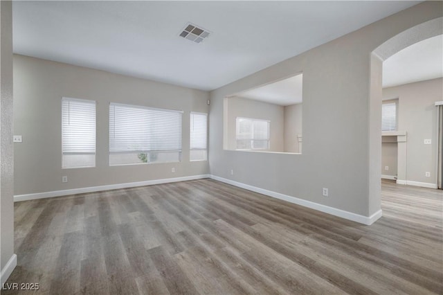 7836 Pinnochio Ave, Las Vegas, NV 89131 - unfurnished room with plenty of natural light, wood finished floors, arched walkways, and baseboards