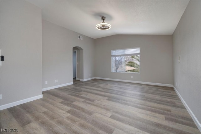 7836 Pinnochio Ave, Las Vegas, NV 89131 - unfurnished room featuring arched walkways, vaulted ceiling, wood finished floors, and baseboards