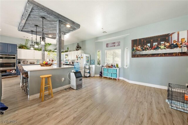 3360 National Ave, Pahrump, NV 89048 - kitchen with freestanding refrigerator, light wood-type flooring, double oven, a center island, and light countertops