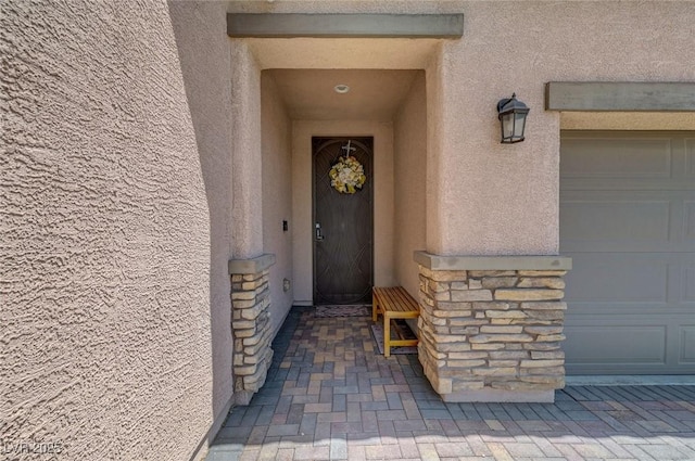 1120 Via Della Curia, Henderson, NV 89011 - doorway to property featuring stucco siding, a garage, and stone siding