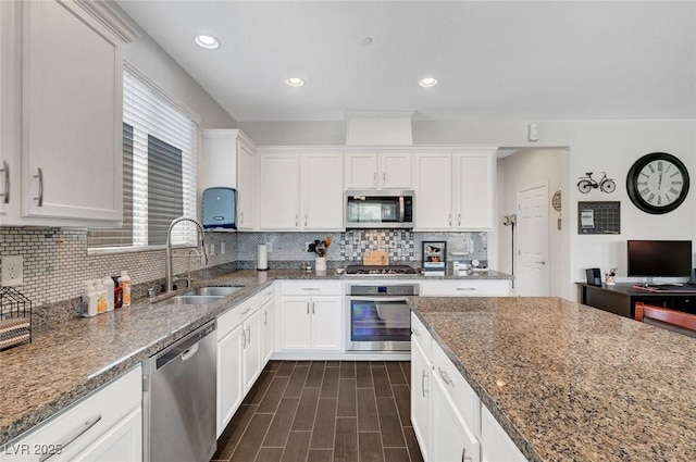 1120 Via Della Curia, Henderson, NV 89011 - kitchen featuring appliances with stainless steel finishes, a sink, white cabinetry, stone counters, and decorative backsplash