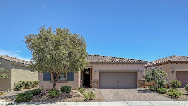 1120 Via Della Curia, Henderson, NV 89011 - view of front of house with an attached garage, stucco siding, stone siding, decorative driveway, and a tile roof