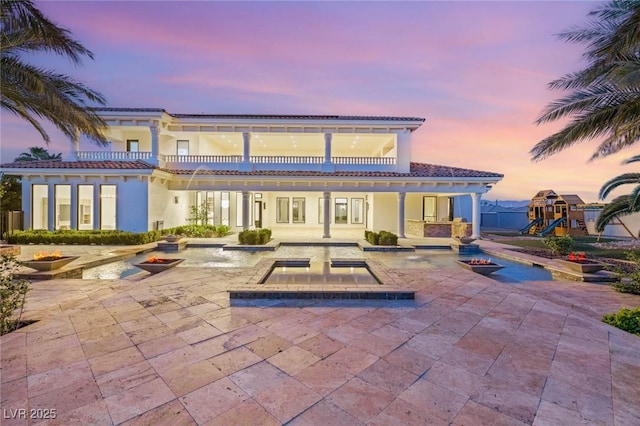 8895 S Tenaya Way, Las Vegas, NV 89113 - back of property at dusk with a patio, a tiled roof, an outdoor fire pit, and a pool with connected hot tub