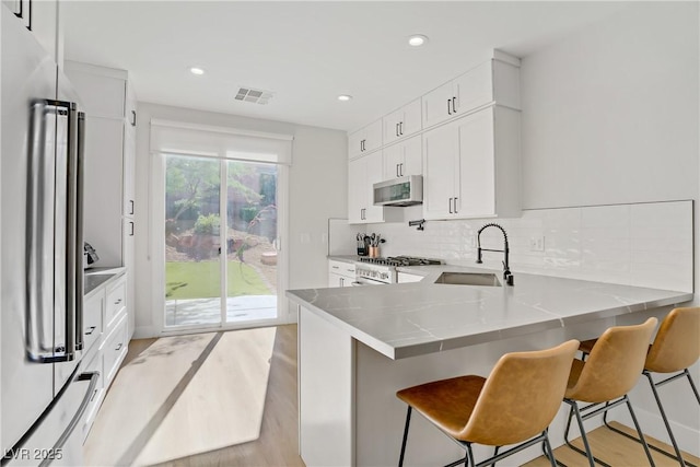305 Napa Hills Dr, Las Vegas, NV 89144 - kitchen featuring stainless steel appliances, light wood-style floors, a peninsula, a kitchen breakfast bar, and recessed lighting
