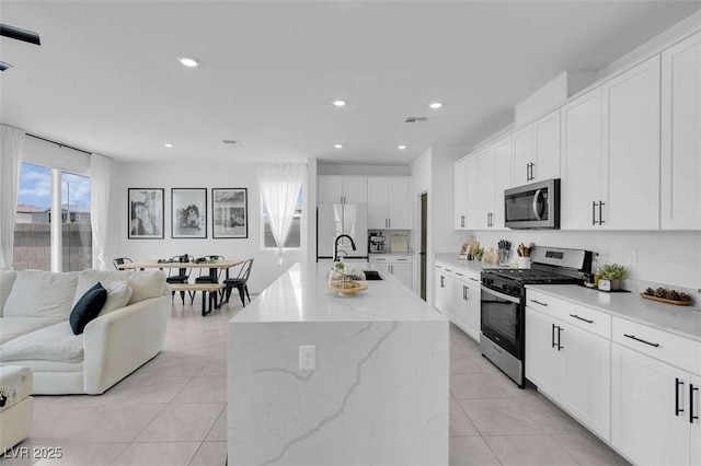 10292 Fragrant Apple Ct, Las Vegas, NV 89141 - kitchen featuring appliances with stainless steel finishes, a sink, open floor plan, light tile patterned flooring, and white cabinets