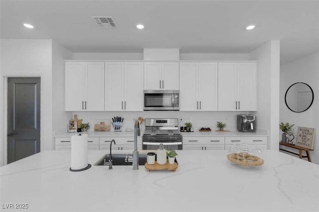 10292 Fragrant Apple Ct, Las Vegas, NV 89141 - kitchen featuring appliances with stainless steel finishes, white cabinetry, recessed lighting, and light stone countertops