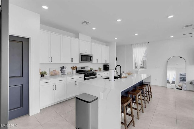 10292 Fragrant Apple Ct, Las Vegas, NV 89141 - kitchen with appliances with stainless steel finishes, a sink, a center island with sink, light tile patterned floors, and recessed lighting