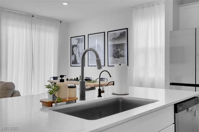10292 Fragrant Apple Ct, Las Vegas, NV 89141 - kitchen with stainless steel dishwasher, a sink, white cabinets, and light countertops