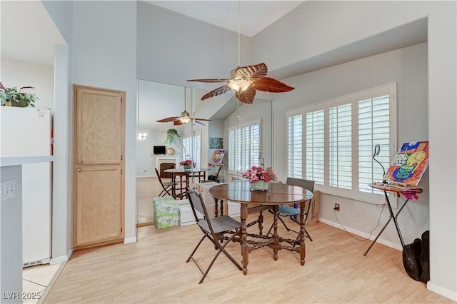 8450 Alta Dr Unit 204, Las Vegas, NV 89145 - dining space featuring light wood-style flooring, a ceiling fan, high vaulted ceiling, baseboards, and a fireplace