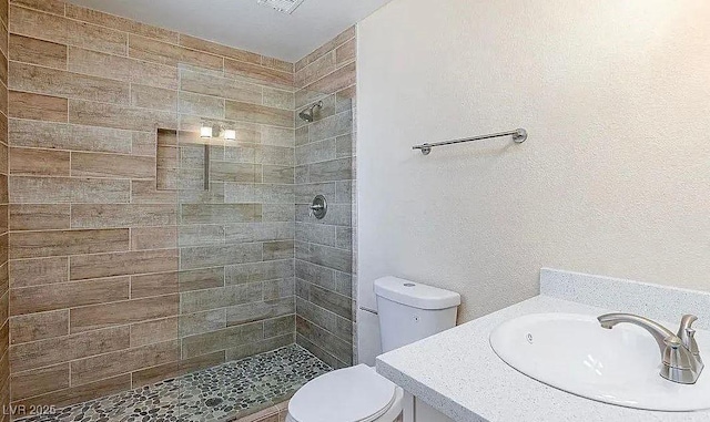 6320 Shawnee Ave, Las Vegas, NV 89107 - full bathroom featuring a tile shower, toilet, vanity, and a textured wall