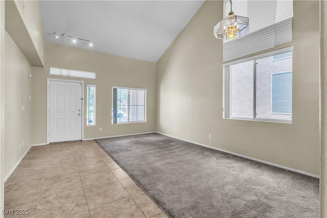 682 E Sole Addiction Ave, Las Vegas, NV 89183 - foyer featuring high vaulted ceiling, carpet, rail lighting, baseboards, and tile patterned floors