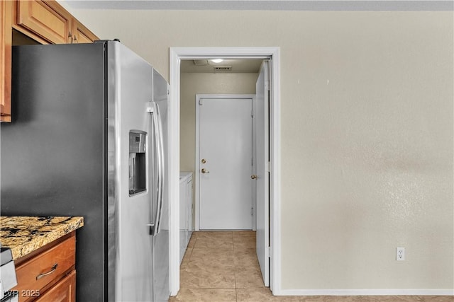 682 E Sole Addiction Ave, Las Vegas, NV 89183 - kitchen featuring stainless steel fridge with ice dispenser, washing machine and dryer, brown cabinets, and light tile patterned flooring