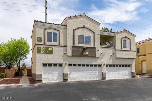 3920 Smokey Fog Ave Unit 201, North Las Vegas, NV 89081 - mediterranean / spanish home with stucco siding, an attached garage, driveway, and a tiled roof
