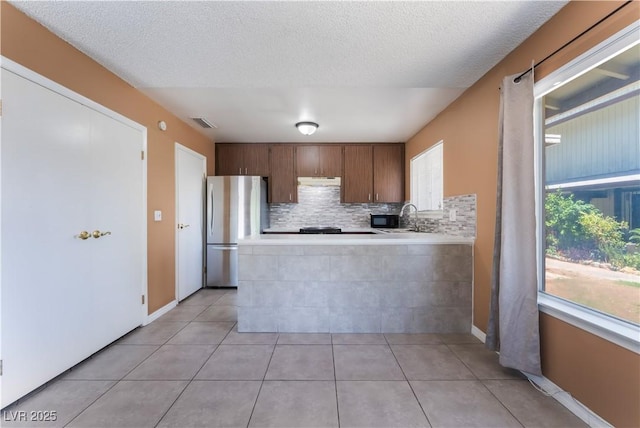 1470 Elizabeth Ave Unit 1, Las Vegas, NV 89119 - kitchen featuring freestanding refrigerator, light countertops, decorative backsplash, a peninsula, and light tile patterned floors
