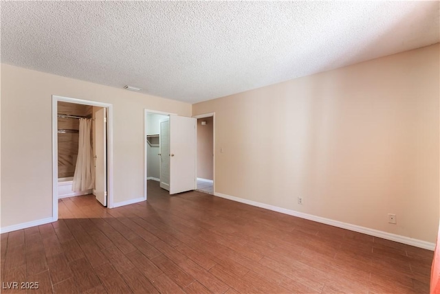 1470 Elizabeth Ave Unit 1, Las Vegas, NV 89119 - unfurnished bedroom featuring wood finished floors, a walk in closet, baseboards, a textured ceiling, and ensuite bath
