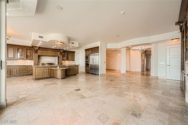 9101 Alta Dr Unit 1203, Las Vegas, NV 89145 - kitchen featuring built in appliances, a chandelier, a kitchen island with sink, and stone tile flooring