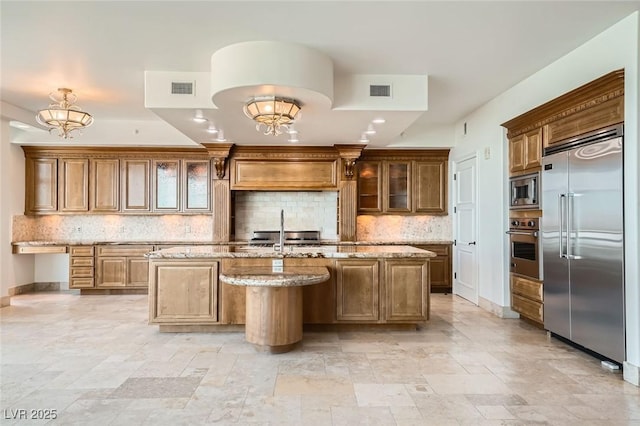9101 Alta Dr Unit 1203, Las Vegas, NV 89145 - kitchen featuring built in appliances, a kitchen island with sink, stone tile flooring, and tasteful backsplash