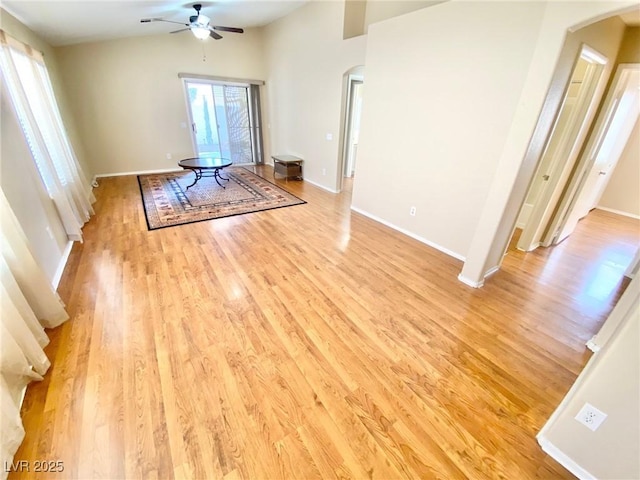 3372 Wayward Ct, Las Vegas, NV 89129 - unfurnished living room featuring arched walkways, a ceiling fan, light wood-style floors, vaulted ceiling, and baseboards
