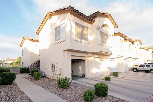 4970 Black Bear Rd Unit 101, Las Vegas, NV 89149 - mediterranean / spanish-style home featuring a tile roof, stucco siding, an attached garage, and stairway