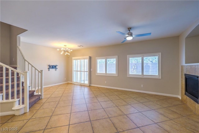 8775 Traveling Breeze Ave Unit 102, Las Vegas, NV 89178 - unfurnished living room with light tile patterned flooring, stairs, a fireplace, a chandelier, and a ceiling fan