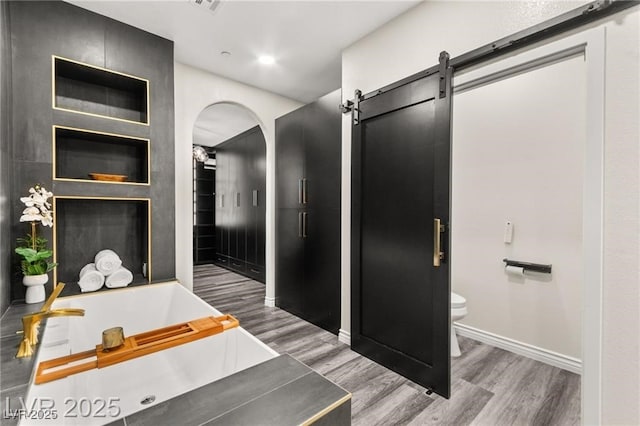 2407 Ridgeline Wash St, Las Vegas, NV 89138 - full bathroom featuring toilet, a garden tub, wood finished floors, and baseboards