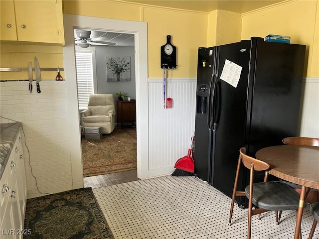 2228 Campton, Ely, NV 89301 - kitchen featuring black fridge, a wainscoted wall, and a ceiling fan