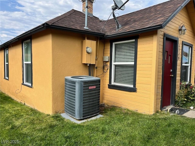 2228 Campton, Ely, NV 89301 - view of side of home featuring central air condition unit, a shingled roof, a yard, and a chimney