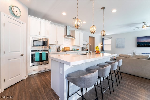 10829 Crestview Pointe Ave, Las Vegas, NV 89166 - kitchen with stainless steel appliances, wall chimney range hood, open floor plan, a sink, and backsplash